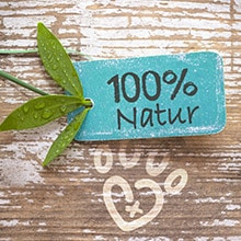 100% Natur Ein Schriftzug vor einem Holz-Hintergrund mit der Aufschrift '100% Natur.'